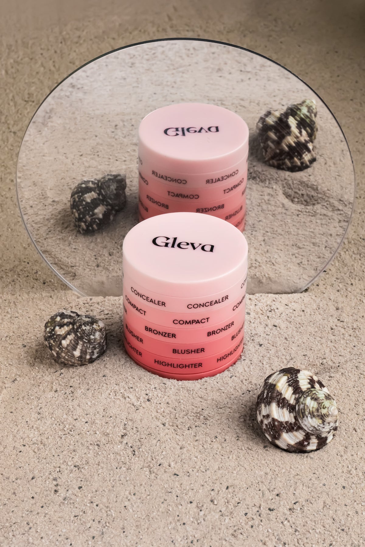 The closed Makeup Stack standing in sand in front of a round mirror