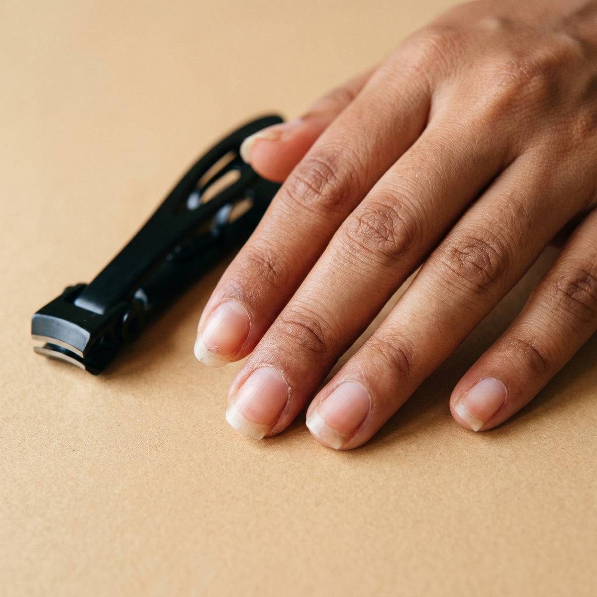 A hand resting beside the black nail clipper
