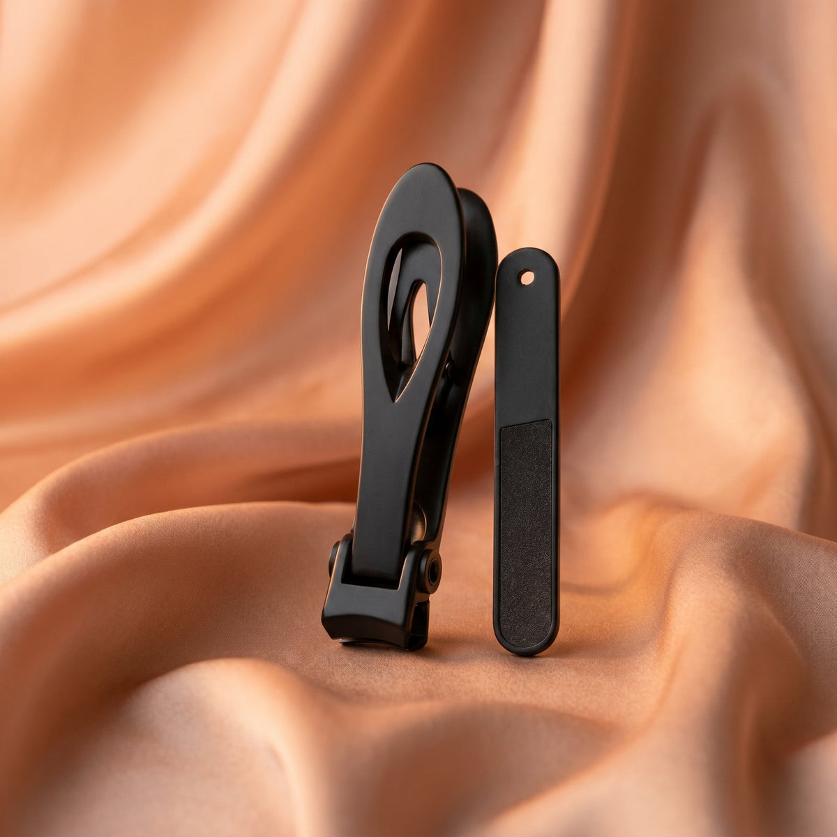 The black wide-jaw nail clipper and nail file standing in peach satin