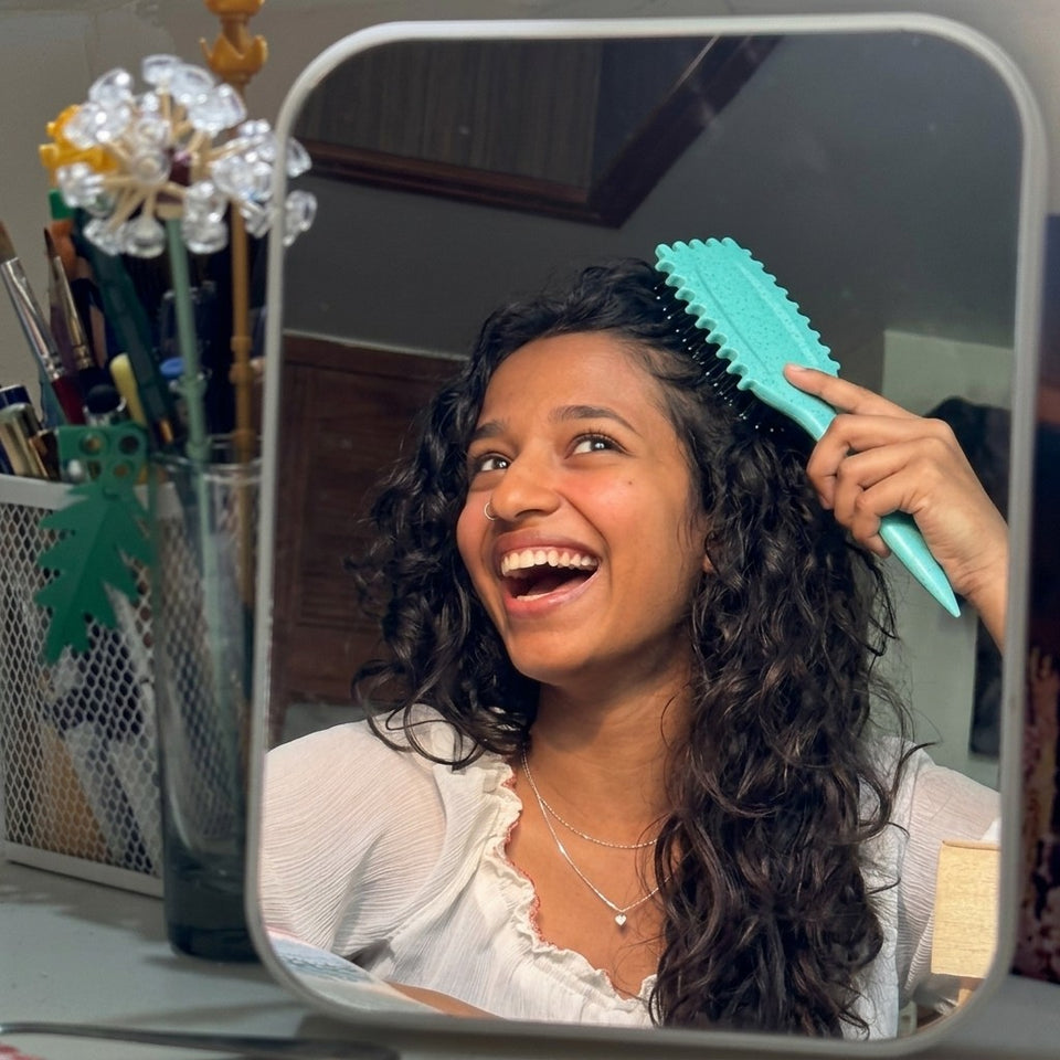 Brushing curls at a mirror with the aqua curl brush